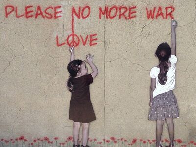 zwei Kinder vor brauner Hauswand mit rotem Graffiti-Schriftzug "Please no more war. Love"
